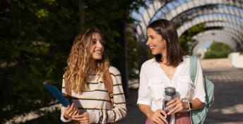 two students smiling and walking outside